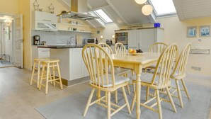 Una cocina amplia con una isla central, sillas de madera y una mesa de comedor.