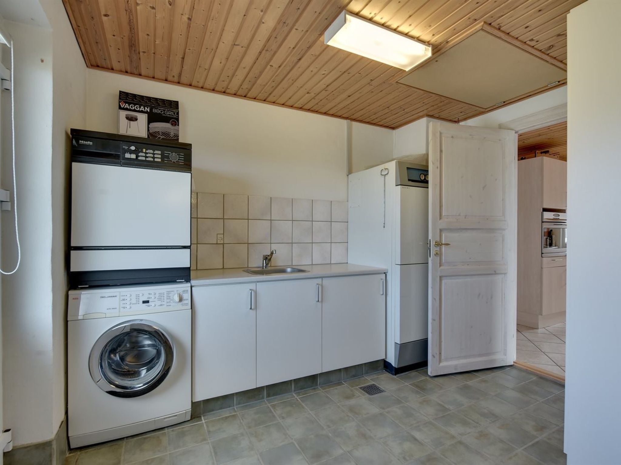A compact kitchen with a washing machine, a refrigerator, and a microwave.