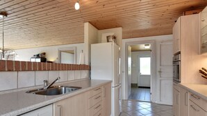Eine moderne Küche mit Holzbalkendecke, integriertem Spülbecken und Kühlschrank.