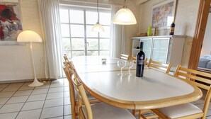 Spiseområde med et rundt bord, træstole og pendellamper.