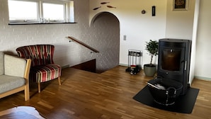 Una sala de estar acogedora con sofá, sillón a rayas, chimenea, ventana y techo de madera.