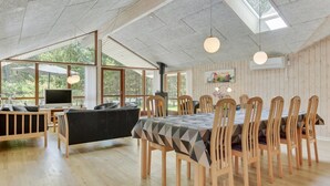 A spacious dining area with a high ceiling, large windows, and a cozy seating area with a fireplace.