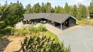 A modern building with a sloped roof, a covered outdoor seating area, and a gravel driveway.