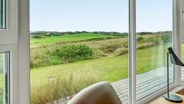 A room with large windows offering a view of a grassy landscape and distant buildings.