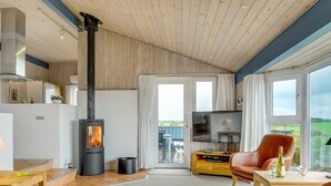 A spacious living area with a wood-burning stove, a television, and a dining area with a table and chairs.