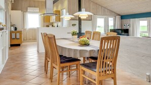 A spacious kitchen with a central island, wooden chairs, and pendant lighting.