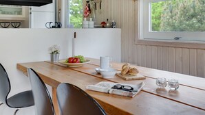 A cozy kitchen with a wooden table, a black hanging light, and a window with a view of greenery. - "Evan" - 1.3km from the sea by Interhome (Pandrup)