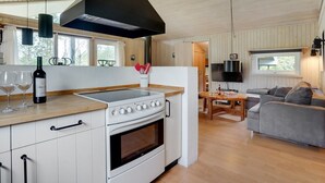 A modern kitchen with a large stove, a dining area with a table and chairs, and a living room with a sofa. - "Evan" - 1.3km from the sea by Interhome (Pandrup)