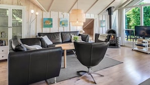 Un salon chaleureux avec une cheminée, des meubles en cuir et des œuvres d’art accrochées aux murs.