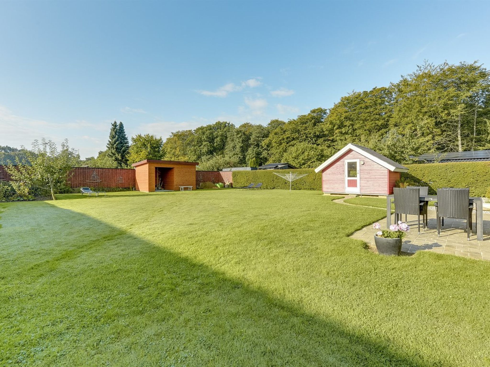 A spacious backyard with a well-maintained lawn, a small wooden shed, and a patio area with outdoor furniture.