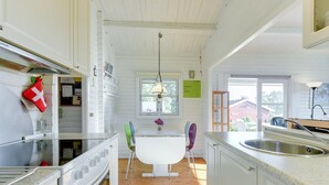 Une cuisine moderne avec des meubles blancs, un plancher en bois, un îlot central doté de chaises et un luminaire suspendu.