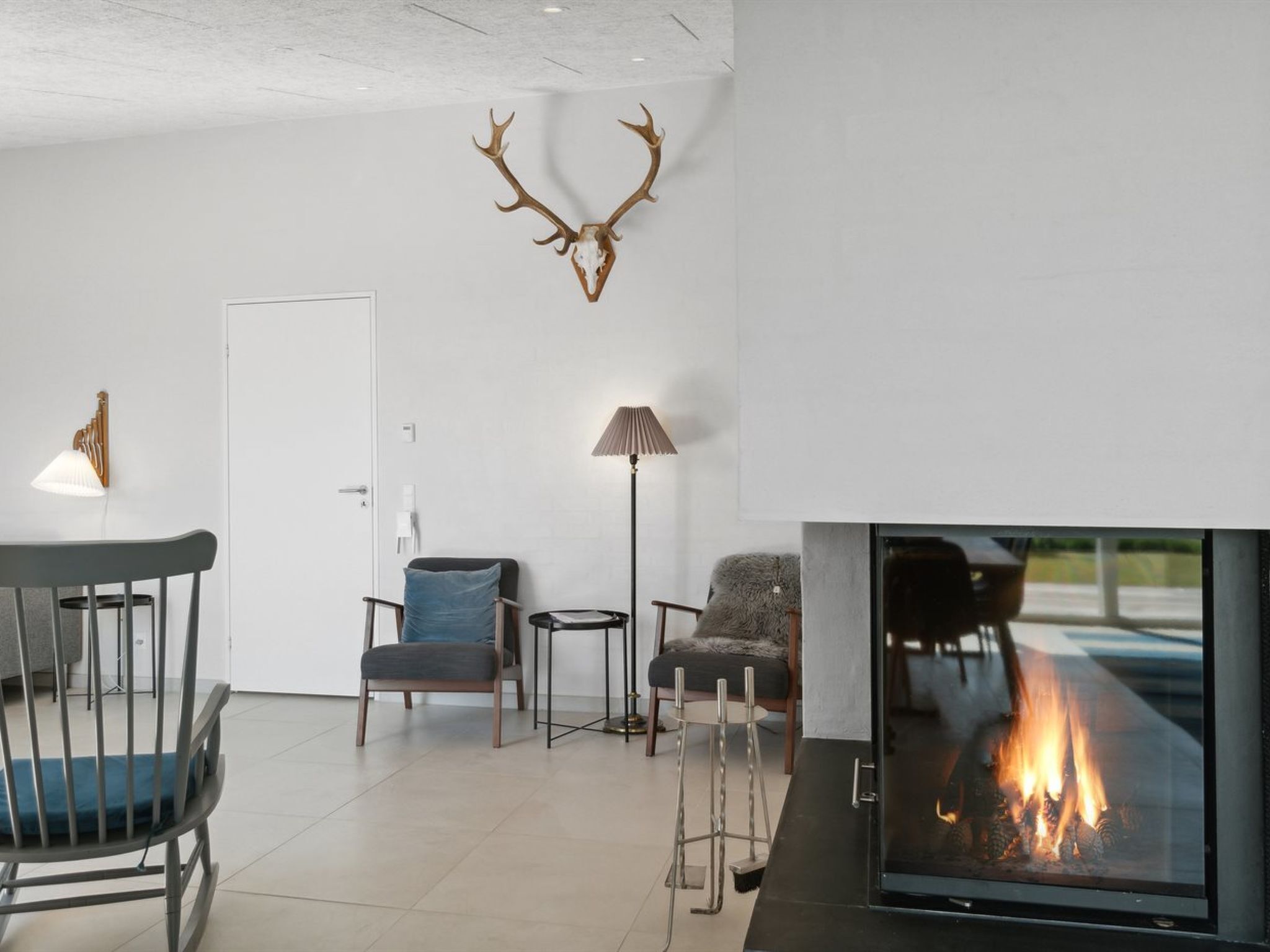 Una sala de estar moderna con chimenea, cráneo de ciervo montado y decoración minimalista.