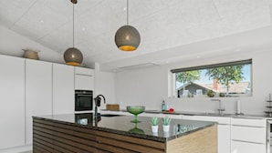 Een moderne keuken met een centraal kookeiland, witte kasten en een groot raam voor natuurlijk licht.