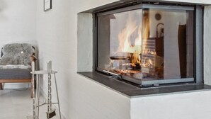 Een moderne woonkamer met een glazen haard, een houten stoel en een metalen standaard.