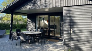 Ett modernt hus med en täckt uteplats, inredd med ett bord och stolar.