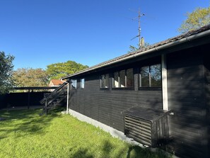 A single-story building with a dark exterior, a satellite dish, and a staircase leading to a covered porch. - "Ady" - 150m from the sea by Interhome (Augustenborg)