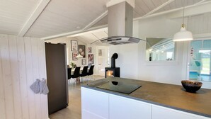 A modern kitchen with a central island, white cabinetry, a black stove, and a hanging pendant light. - "Sirka" - 200m from the sea by Interhome (Vejers Strand)