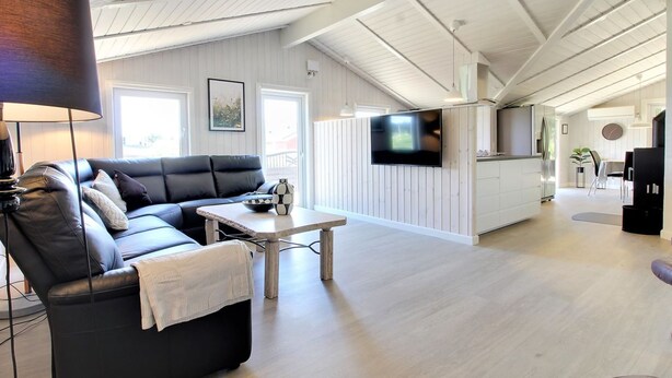 A modern living room with a black leather sofa, a coffee table, and a flat-screen TV mounted on the wall. - "Sirka" - 200m from the sea by Interhome (Vejers Strand)