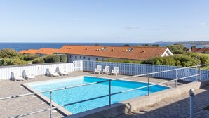 Ein Dachpool mit Liegestühlen, ein freier Blick auf das Meer und im Hintergrund Gebäude mit Terrakotta-Dächern.