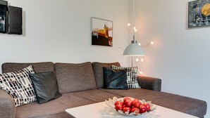 Ein modernes Wohnzimmer mit einem grauen Sofa, einem weißen Couchtisch und einer Schüssel mit Äpfeln.