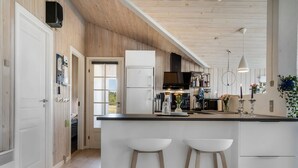 A modern kitchen with a large island, wooden accents, white cabinetry, and a view to the outdoors.