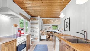 Une cuisine moderne avec des meubles en bois, un grand îlot central doté d’un évier et une vue sur l’extérieur.