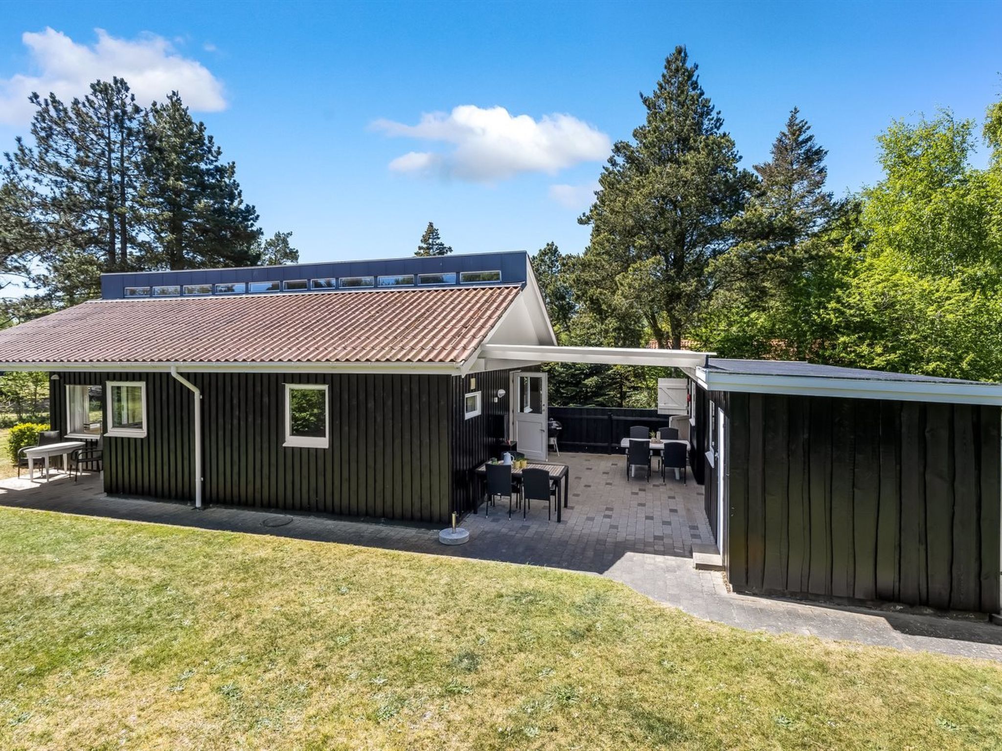 A modern house with a patio area, a covered outdoor seating area, and a garage.