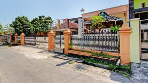 Un barrio residencial con entrada protegida, un jardín cuidado y una casa con tejado de tejas.