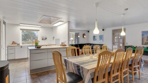 Une cuisine moderne avec un coin repas, comprenant un îlot central, des chaises en bois et une table de billard.