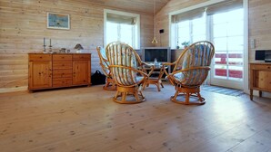 Un interior de madera con comedor que incluye sillas de mimbre, un mueble de madera y un televisor.