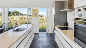 Una cocina moderna con una isla grande, horno empotrado y vistas a través de la puerta de cristal.