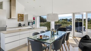 Una cocina moderna con una mesa de comedor de vidrio, sillas negras y vistas al exterior.