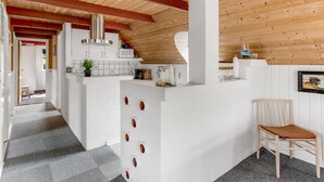 Una cocina moderna con armarios blancos, una campana de acero inoxidable y techo de madera.