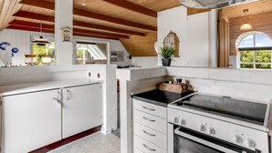 Una cocina moderna con armarios blancos, encimera negra y campana extractora de acero inoxidable.