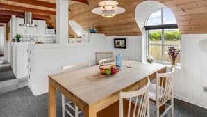 Una cocina amplia con armarios blancos, una mesa de comedor de madera y un ventanal grande.