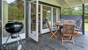 Eine Terrasse im Freien mit Grill, Tisch und zwei Stühlen.
