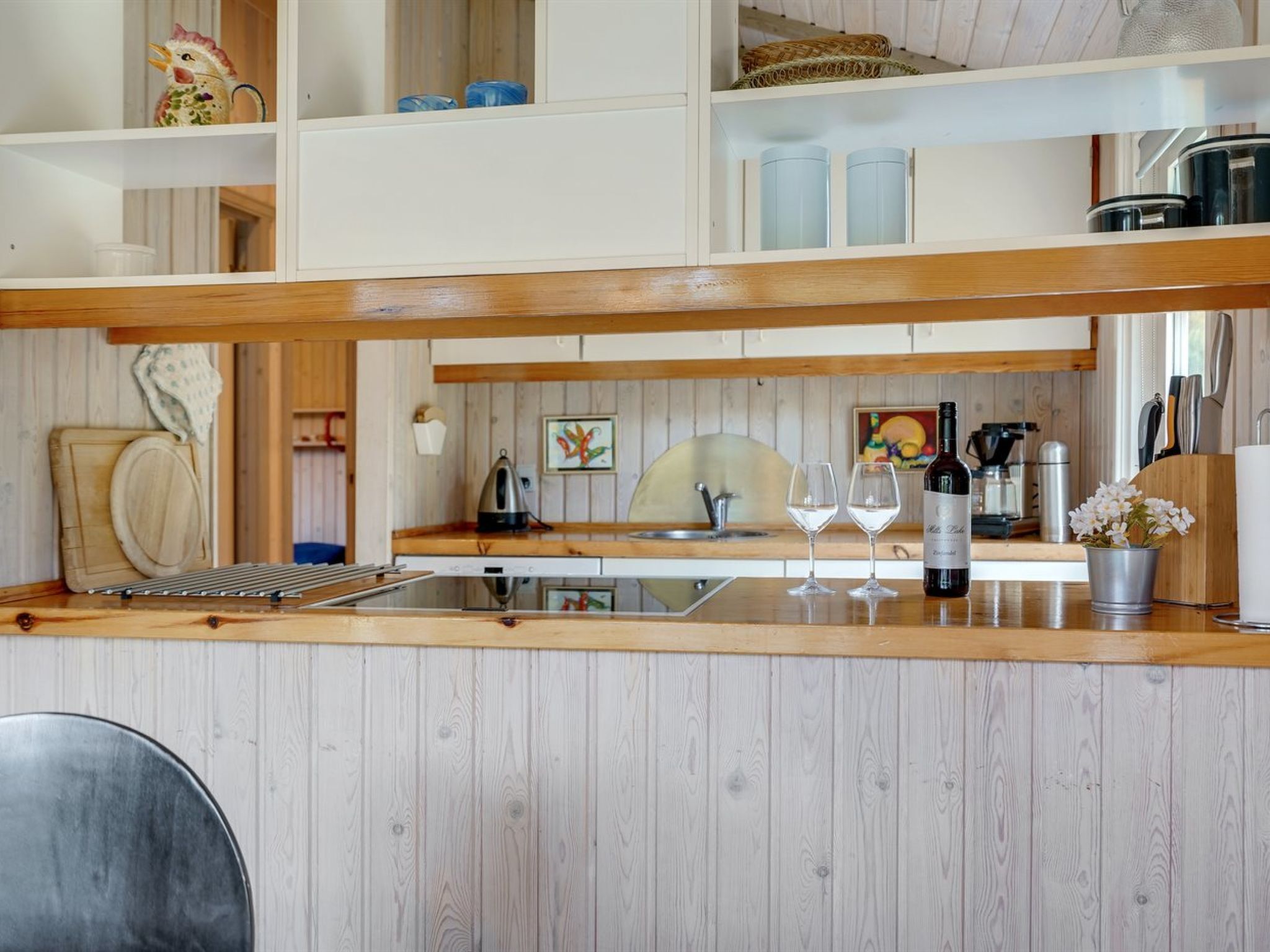 Une cuisine avec un plan de travail en bois, un évier et une bouteille de vin.