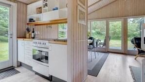 Eine moderne Küche mit weißen Schränken, einem eingebauten Backofen und einem Essbereich mit Tisch und Stühlen.