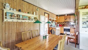 A wooden interior with a dining table, chairs, a kitchen area, and shelves with various items. - "Carita" - 500m from the sea by Interhome (Glesborg)