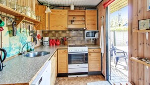 A compact kitchen with wooden cabinets, a microwave, and a stove. - "Carita" - 500m from the sea by Interhome (Glesborg)