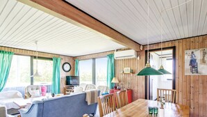 A cozy room with a wooden ceiling, a sofa, a TV, a dining table with chairs, and a large window with curtains. - "Carita" - 500m from the sea by Interhome (Glesborg)