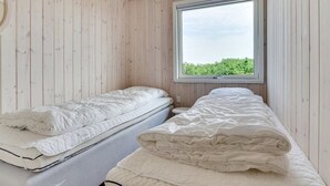 Un dormitorio con dos camas, paredes de madera y una ventana con vistas a zonas verdes.