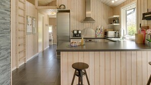 Eine moderne Küche mit Holzvertäfelung, einem Edelstahlkühlschrank, einem Einbauofen und einer großen Kücheninsel mit Barhocker.