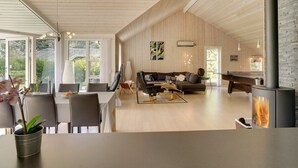 Ein großzügiger Wohnbereich mit Holzboden, einem Kamin und einem Essbereich mit Tisch und Stühlen.