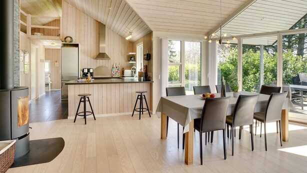 Eine moderne Küche mit Holzvertäfelung, einer Kochinsel und Barhocker.