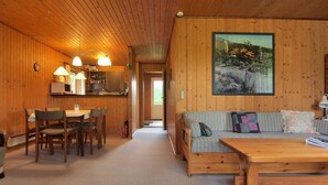 L’intérieur d’un chalet accueillant, avec un coin repas, un canapé et un tableau accroché au mur.