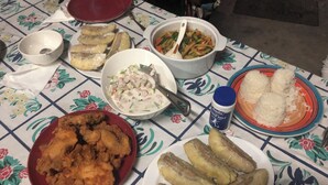 A table with various dishes including fried chicken, pickles, and a salad. - Jaymy Beach Fales (Saleapaga)