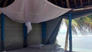 A bed with a canopy in a room with a view of the ocean. - Jaymy Beach Fales (Saleapaga)