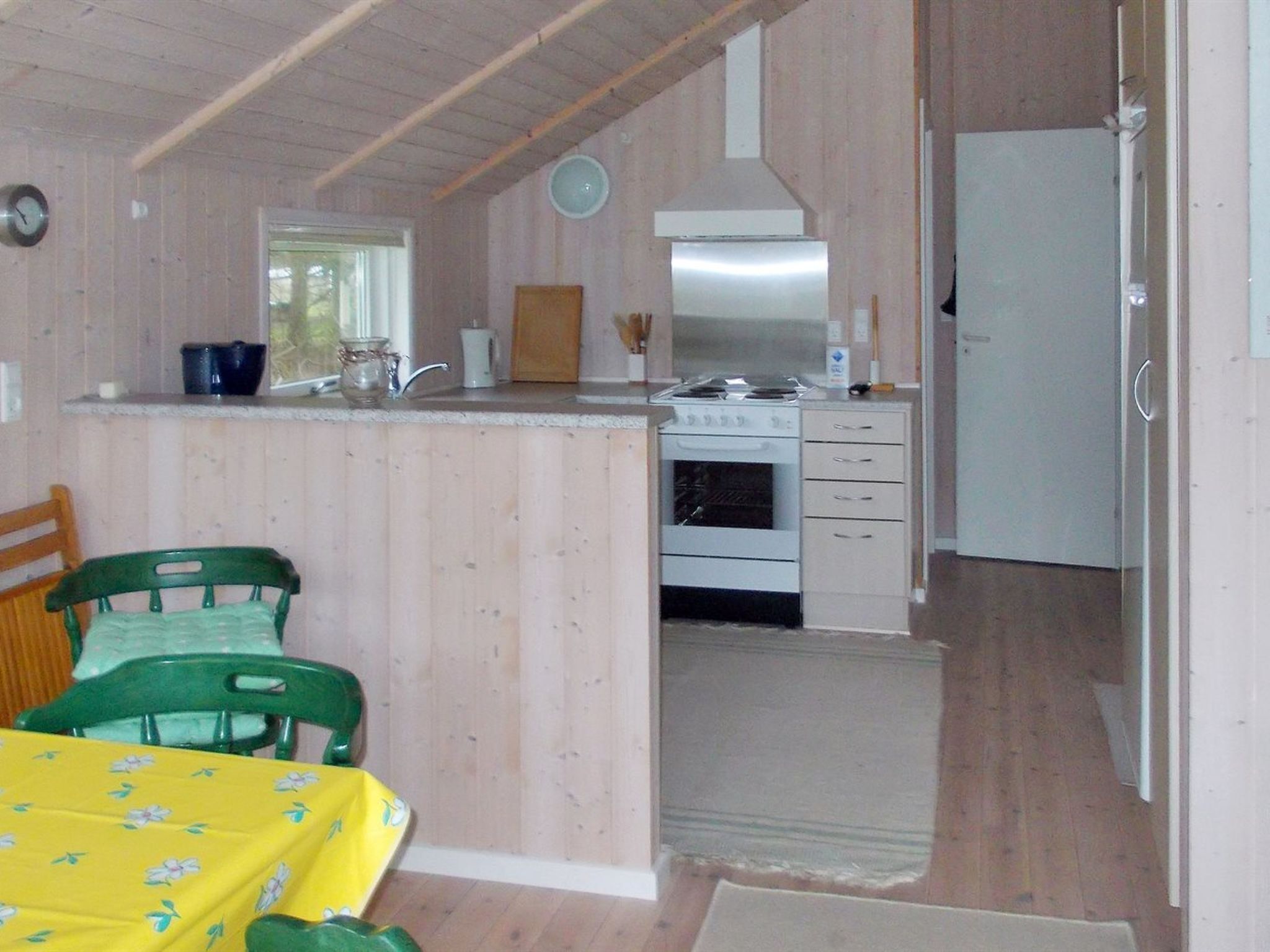 Una cocina compacta con estufa, pileta y refrigerador. Cuenta con un comedor con mesa y sillas.