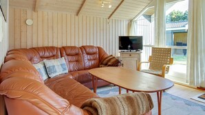 Een gezellige woonkamer met een leren hoekbank, een houten salontafel en een televisie op een houten kast.
